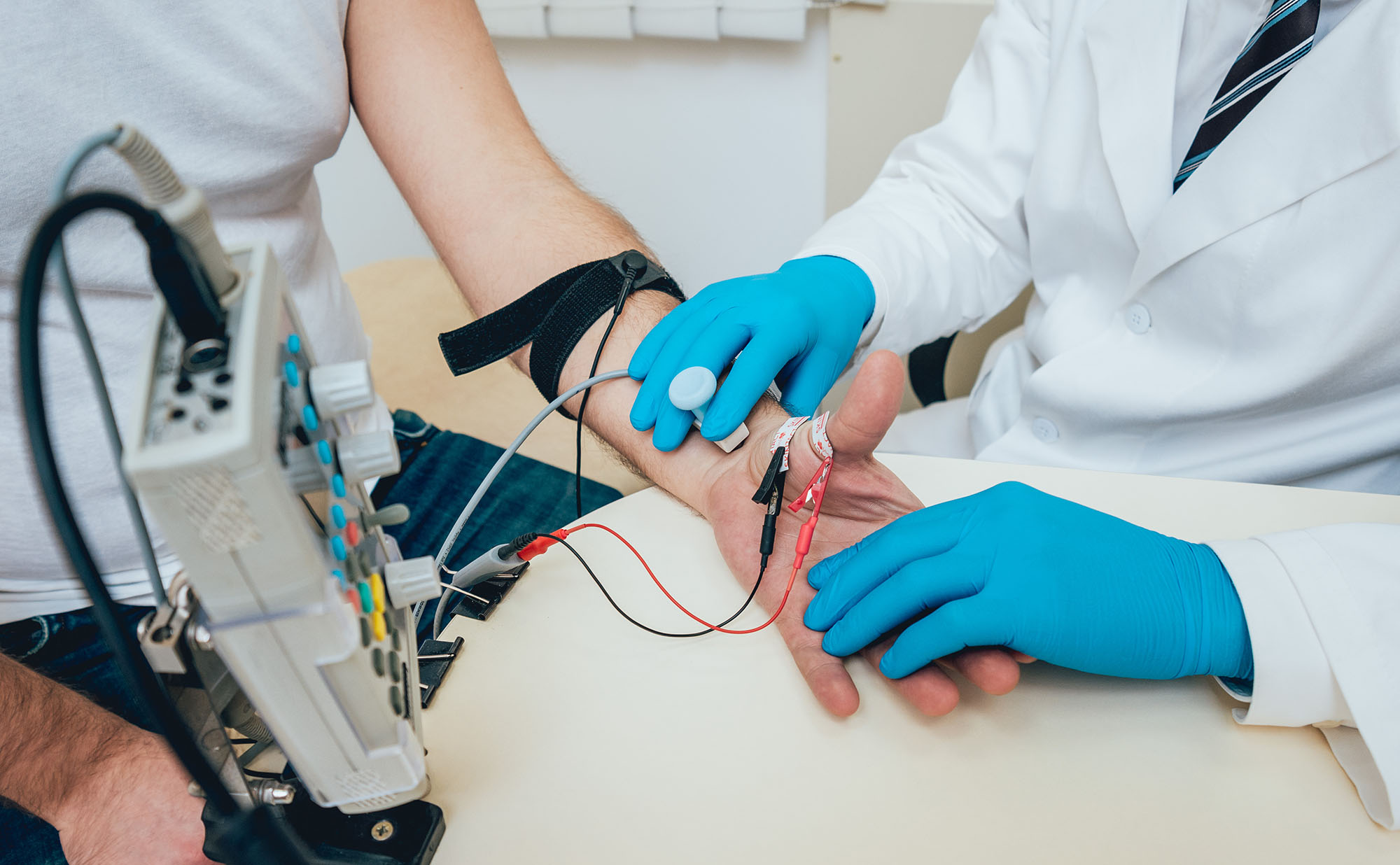 Clinician performing a nerve conduction study on a patient's hand